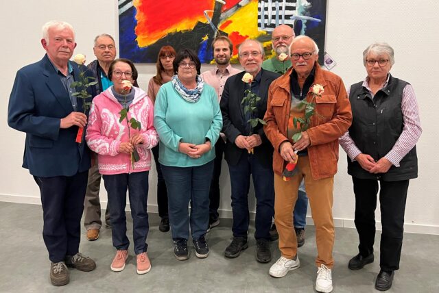 Helmut Lenk, Friedhelm Frey, Renate Lenk, Marianne Modner, Sabine Simon-Lewe, Christopher Lewe, Rainer Lewe, Hartmut Weissenbacher, Lothar Grabosch, Ursula Weissenbacher stehen für ein Foto zusammen. Einige von ihnen halten eine Rose in der Hand.