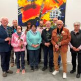 Helmut Lenk, Friedhelm Frey, Renate Lenk, Marianne Modner, Sabine Simon-Lewe, Christopher Lewe, Rainer Lewe, Hartmut Weissenbacher, Lothar Grabosch, Ursula Weissenbacher stehen für ein Foto zusammen. Einige von ihnen halten eine Rose in der Hand.