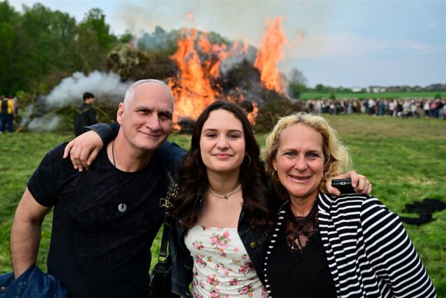 Zwei Frauen und ein Mann stehen vor dem lodernden Osterfeuer am Hof von Karl Godde in Herten-Disteln.