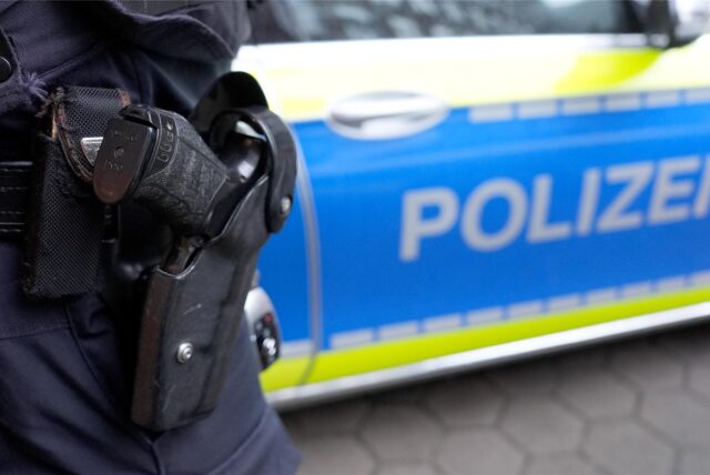 Ein Polizist steht vor einem Einsatzfahrzeug der Polizei. (Symbolbild)