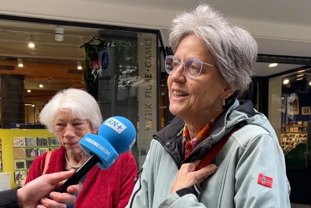 Eine Frau sitzt auf einer Bank in Dortmund und spricht in ein Mikrofon.