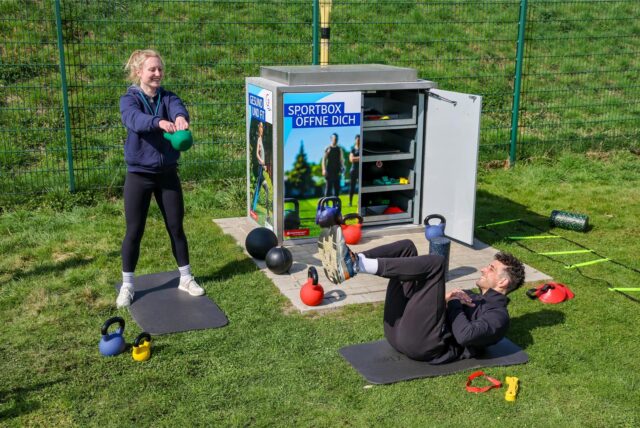 Ein Paar bewegt sich vor einer Sportbox.