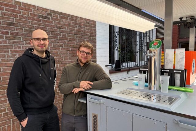 Matthias Tewes und Florian Höwing stehen neben ihm großen Maiwagen