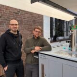 Matthias Tewes und Florian Höwing stehen neben ihm großen Maiwagen