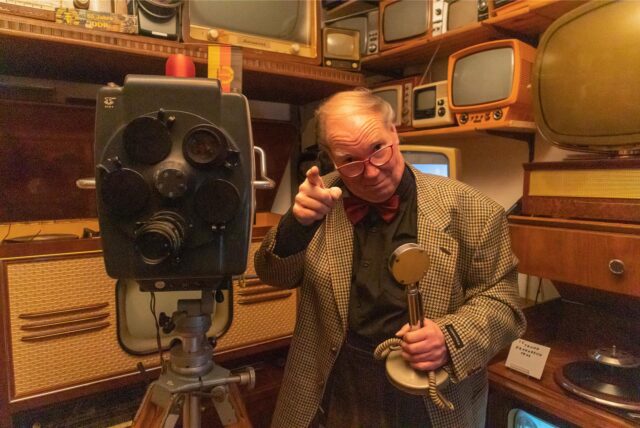 Rainer Berkenhoff umgeben von alten Radios und Fernsehgeräten