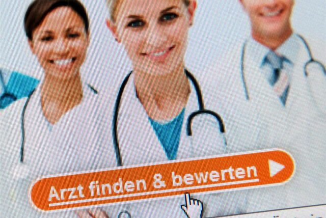 Drei Ärzte auf einem Monitor, der die Startseite eines Internetportals zeigt.