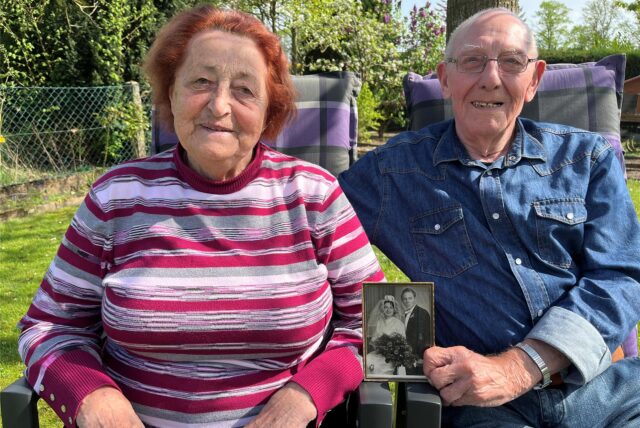 Eveline und Adolf Sandkühler sitzen unter ihrem Walnussbaum im Garten. Adolf hält ihr Hochzeitsfoto in den Händen.