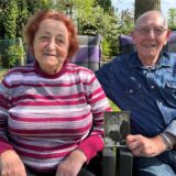 Eveline und Adolf Sandkühler sitzen unter ihrem Walnussbaum im Garten. Adolf hält ihr Hochzeitsfoto in den Händen.