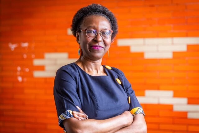 Porträtfoto von Vaye Tatah vor einer orangefarbenen Wand in ihrem Büro in Dortmund, in dem auch der Redaktionssitz des Magazins Africa Positive untergebracht ist.