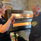 Sabrina Macher und Marco Paper vom Drügen-Pütt in Haltern stehen lachend vor ihrem neuen Pizzaofen.