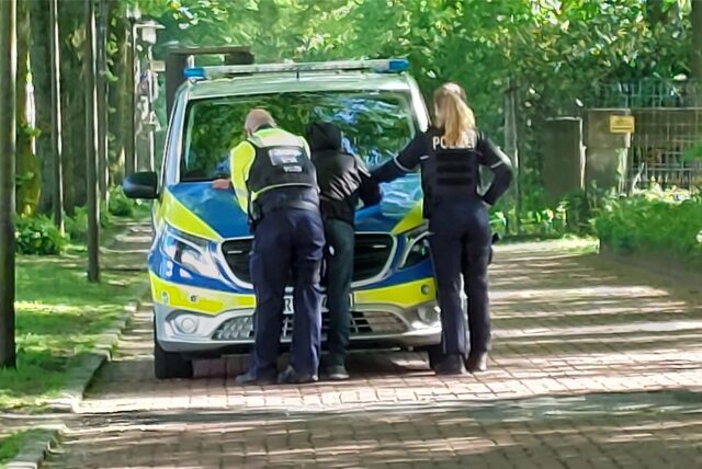Zwei Polizeibeamte halten vor einem Streifenwagen am Einkaufszentrum Marler Stern einen Mann fest.
