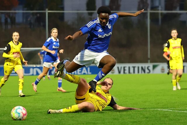 Eine Fußballerin von Schalke 04 springt über die Grätsche einer Spielerin des BVB.
