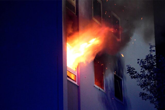 Flammen schlagen aus einem Fenster einer Wohnung.