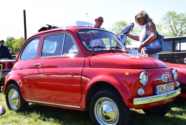 Ein Mann und eine Frau betrachten einen roten Fiat-500-Oldtimer auf dem Prickingshof in Haltern-Sythen.