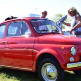 Ein Mann und eine Frau betrachten einen roten Fiat-500-Oldtimer auf dem Prickingshof in Haltern-Sythen.