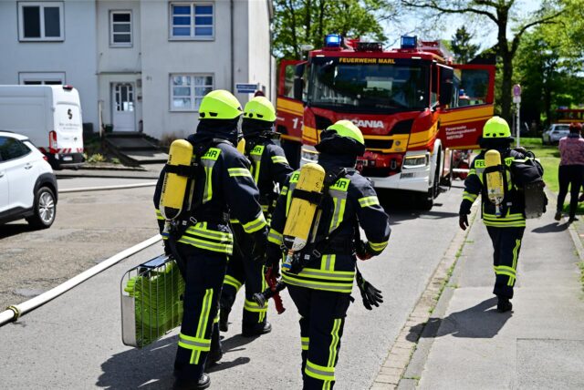 Feuerwehrleute in Montur gehen zum Einsatzfahrzeug.