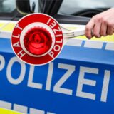 Ein Polizist hält eine Polizeikelle für eine Kontrolle auf einem Parkplatz an der Autobahn