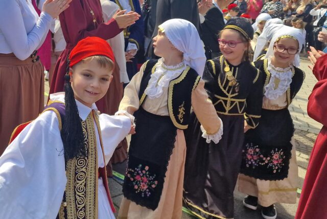 Kinder in Trachtenkleidung ziehen durch die Menschenmenge.