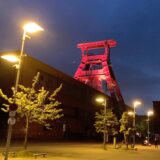 Abendaufnahme der Zeche Ewald in Herten-Süd mit dem rot angestrahlten Förderturm.