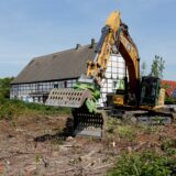 Vor Fachwerkhäusern in Bergkamen steht ein Abrissbagger.
