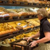Eine Bäckerei-Fachverkäuferin sortiert Brote aus dem Korb ins Regal.