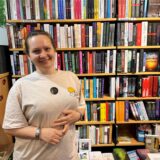 Natalia Tokar-Kahn lächelt in die Kamera, hinter ihr ein großes Bücherregal.