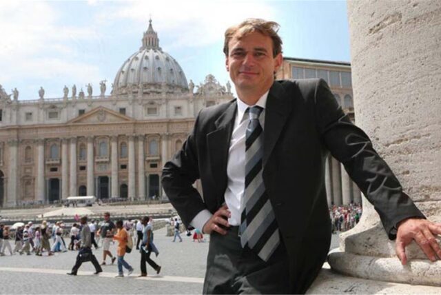 Andreas Englisch steht vor dem Petersdom im Vatikan. Im Hintergrund sind weitere Personen zu sehen.
