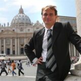 Andreas Englisch steht vor dem Petersdom im Vatikan. Im Hintergrund sind weitere Personen zu sehen.
