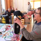 Ein Mann sitzt beim Repai-Café im Februar 2025 im Gemeindezentrum der Thomaskirche in Westerholt an einem Tisch, hält ein Elektrogerät in der linken und einen Schraubendreher in der rechten Hand.