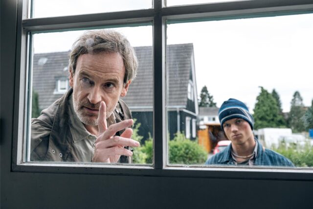 Hauptkommissar Peter Faber (Jörg Hartmann) und Finn Gebken (Caspar Hoffman, r), Sohn der toten Meike Gebken stehen im Dortmund-Tatort „Feuer“ vor einem Fenster.