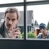 Hauptkommissar Peter Faber (Jörg Hartmann) und Finn Gebken (Caspar Hoffman, r), Sohn der toten Meike Gebken stehen im Dortmund-Tatort „Feuer“ vor einem Fenster.