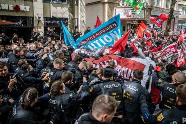 Schwarz uniformierte Polizisten und Demonstranten mit Flaggen geraten aneinander.