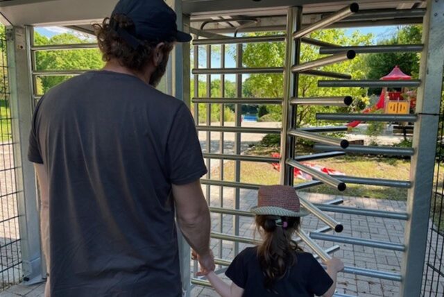 Ein Vater und seine Tochter stehen vor dem geschlossenen Eingang zum Freibad Wellinghofen.