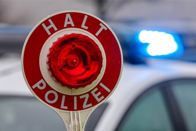 Ein Polizist hält eine Polizeikelle für eine Kontrolle. (Symbolbild)