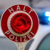 Ein Polizist hält eine Polizeikelle für eine Kontrolle. (Symbolbild)