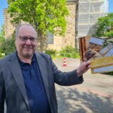 Ein Mann steht vor der Lutherkirche in Datteln und hält vier Karten in der Hand.