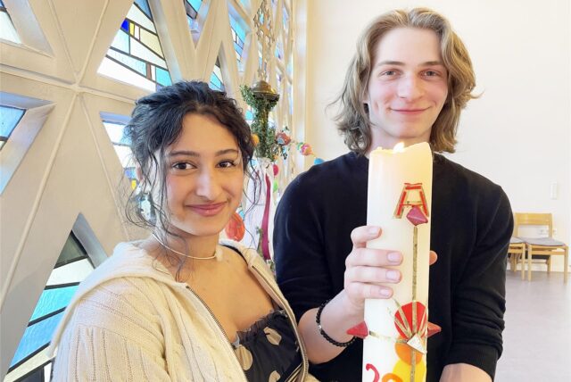 Die Christen Mia und Benjamin halten in der alt-katholischen Kirche in Kley eine Kerze in der Hand.