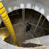 Ein Schlauch führt hinunter in den Eisspeicher des Solarhauses in Kamen. Unten steht ein Mann.