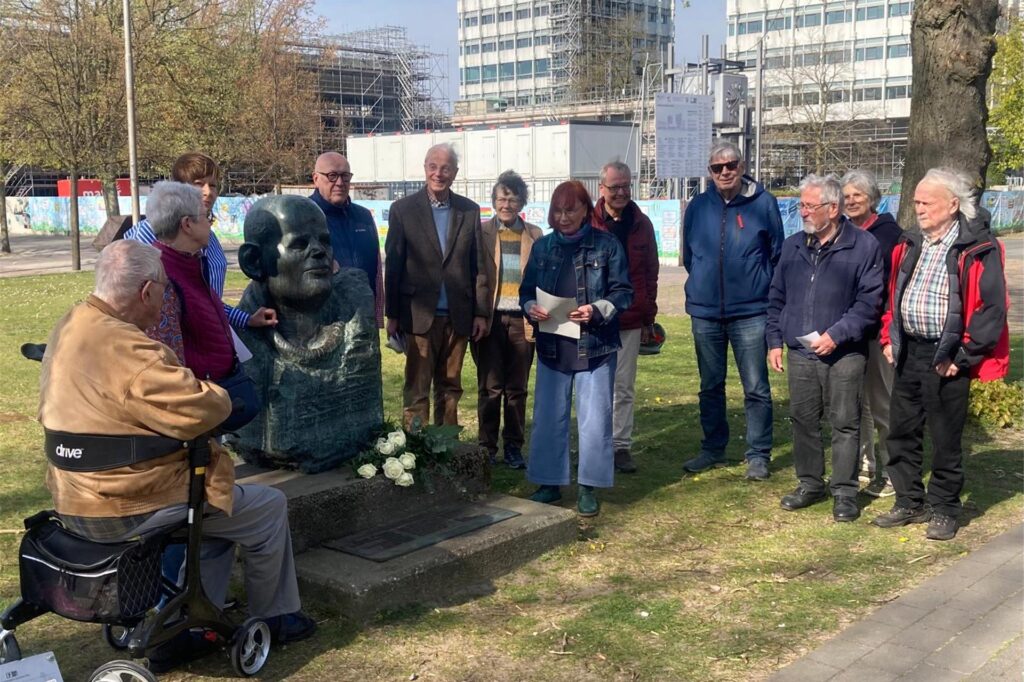 Eine Menschengruppe steht um eine Statue von Dietrich Bonhoeffer. Eine Menschengruppe steht um eine Statue von Dietrich Bonhoeffer.
