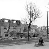 Ein Kind sitzt 1945 auf einem Wagen vor den Ruinen zerstörter Häuser in der Zechenstraße in Datteln.