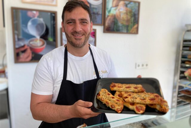 Sleiman Kalach steht im Lieblingscafe in Herten-Süd hinter der Theke und präsentiert Backwaren.