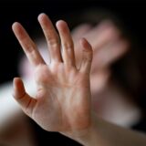 Eine Frau hebt schützend ihre Hand.