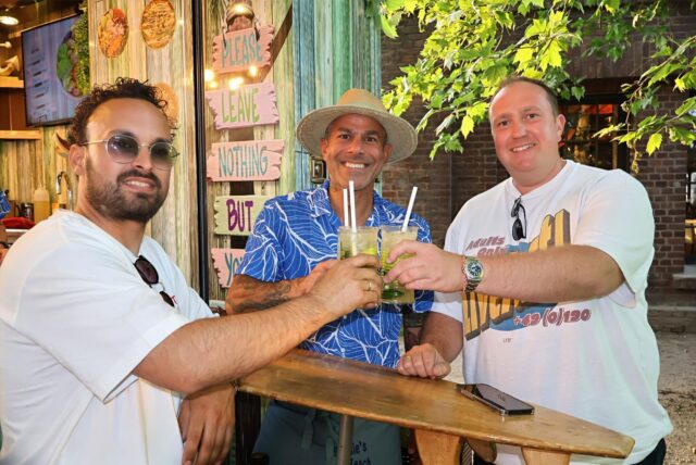 Drei Männer stoßen mit Cocktails an