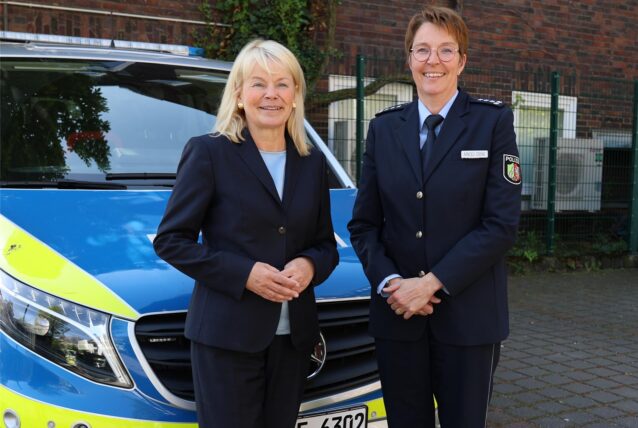 Zwei Frauen stehen vor einem Polizeiwagen.