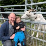 Vater und Sohn stehen vor einem Ziegengehege