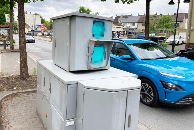 Ein blauer Pkw fährt auf der Ewaldstraße in Herten-Süd an dem Panzerblitzer vorbei, dessen Fenster mit blauer Farbe besprüht worden sind.
