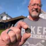 Gunther Berse hält seinen wiedergefundenen Kettenanhänger zwischen Daumen und Zeigefinger.