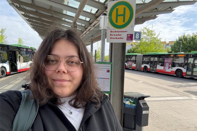 Laura Wunderlich steht vor dem Haltestellenschild des Schienenersatzverkehrs in Marl-Mitte.