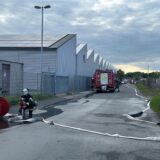Blick auf die Zufahrt der Maschinenhallen, in der einige Löschfahrzeuge stehen und ein Löschschlauch ausgerollt ist