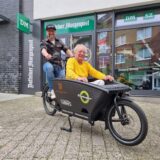 Zwei Männer sitzen in einem Lastenfahrrad.